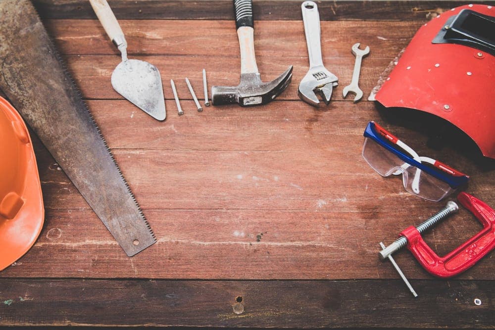 Hand tools and safety glasses laid out on a wooden workbench