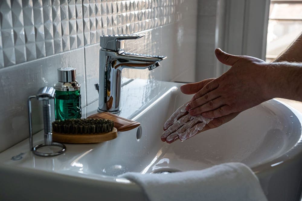 Hands being lathered with soap at a bathroom sink