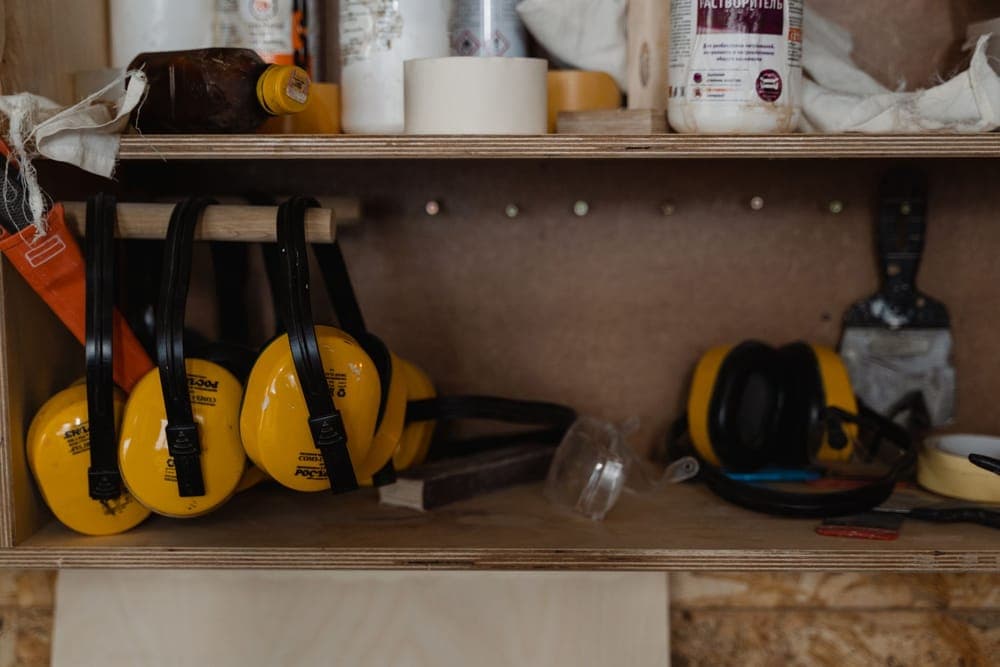 Yellow earmuffs hanging on a shelf in a workshop