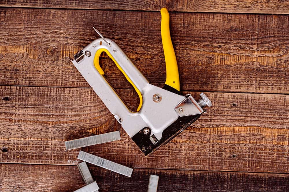 Illustrative stock photo: a staple gun and staples on a wooden surface