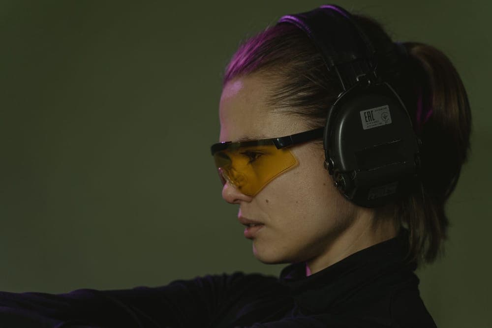 A woman wearing amber-tinted safety glasses and earmuffs